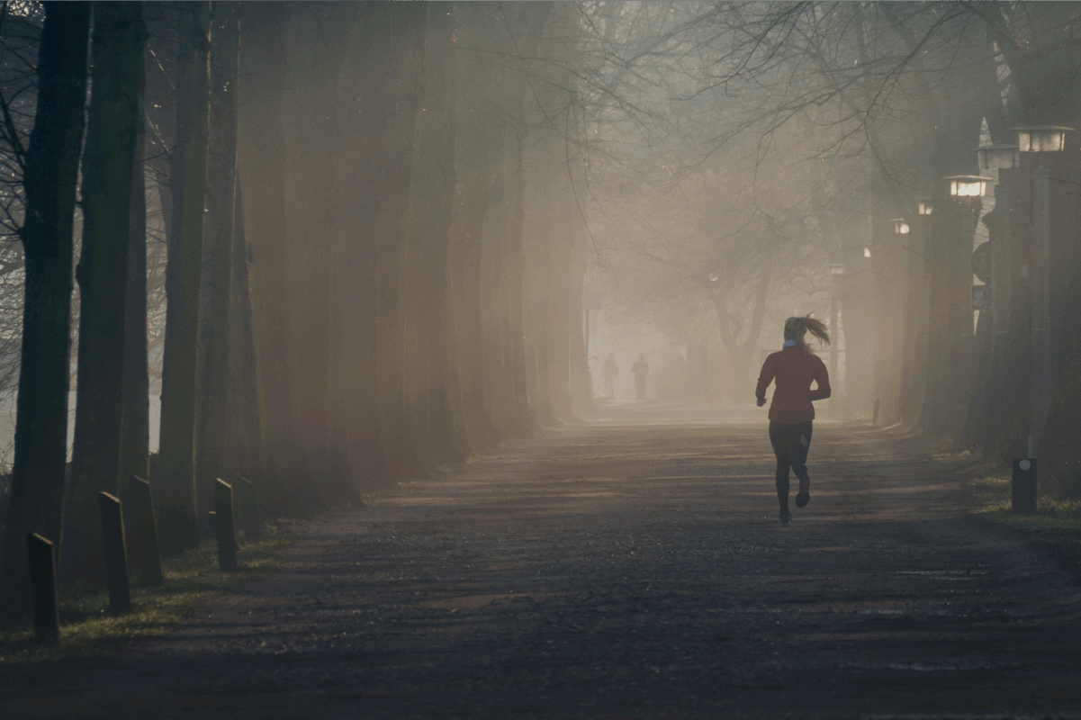 woman running in a foggy park during winter