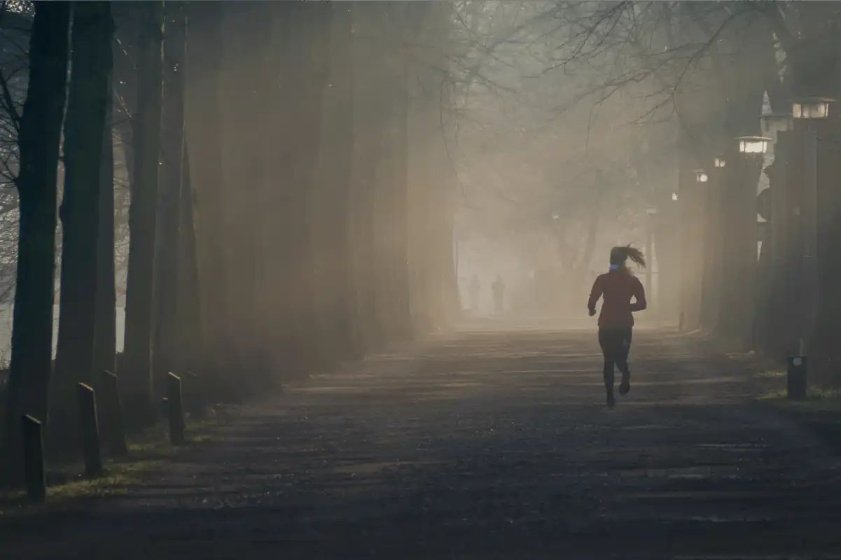 woman running in a foggy park during winter